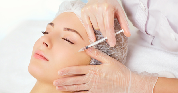 Woman lying down receiving a Botox injection near her forehead