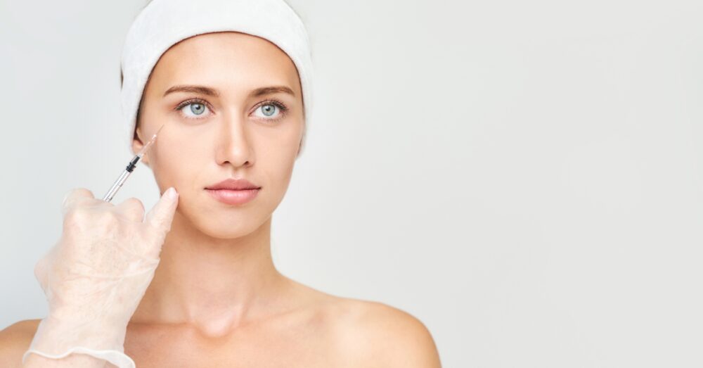 A woman wearing a white headband receiving a cosmetic injectable treatment