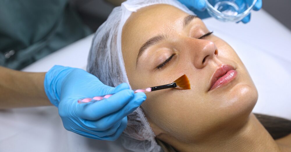 Woman with eyes closed receiving a skin treatment from a gloved provider